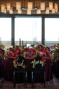 wedding table flowers candles pink purple red gold bride and groom signs