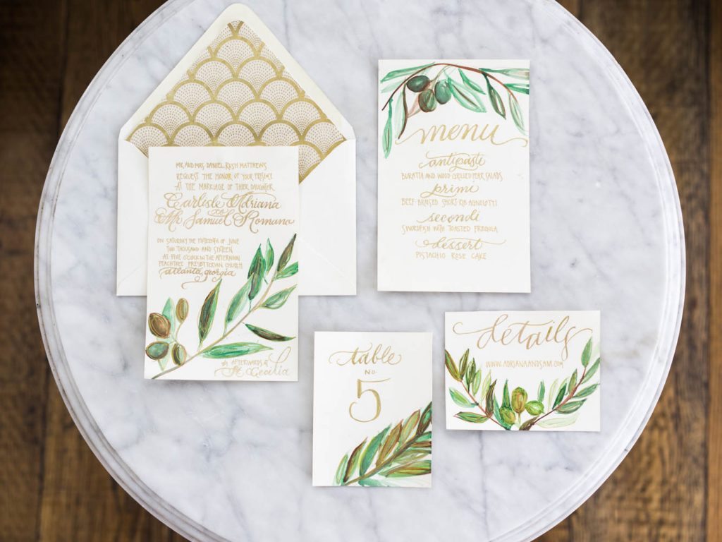 gold calligraphy wedding invitations with green leaf details