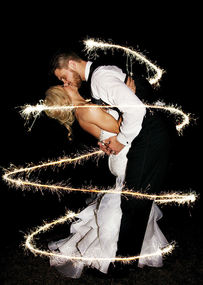Bride and groom kissing sparklers